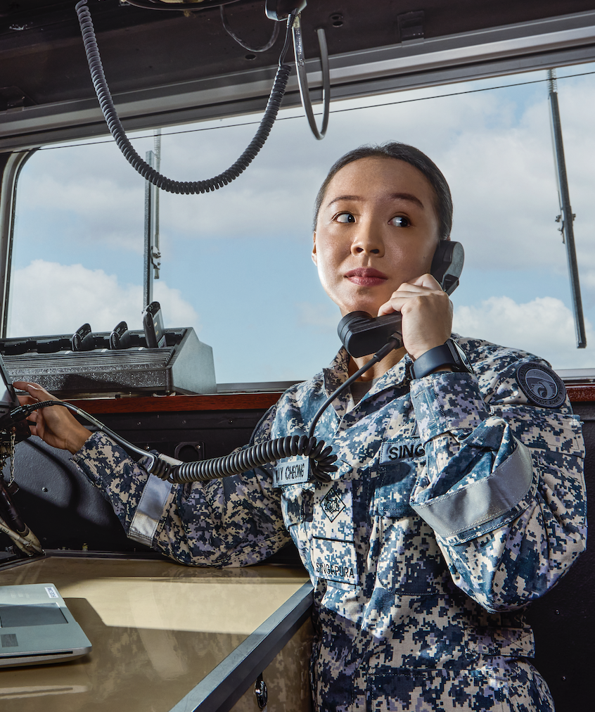 Female sailor uses communication console while speaking on a phone in a ship